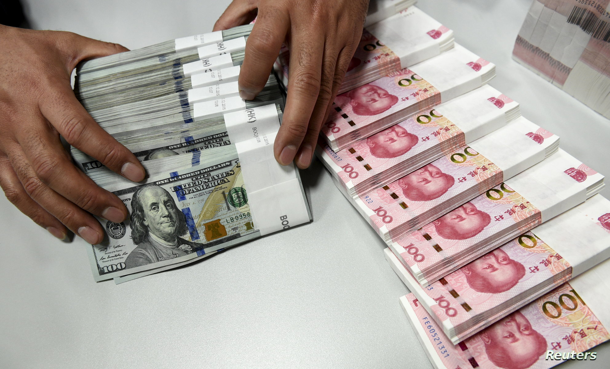 A clerk counts Chinese yuan and U.S. dollar banknotes at a branch of Bank of China in Taiyuan