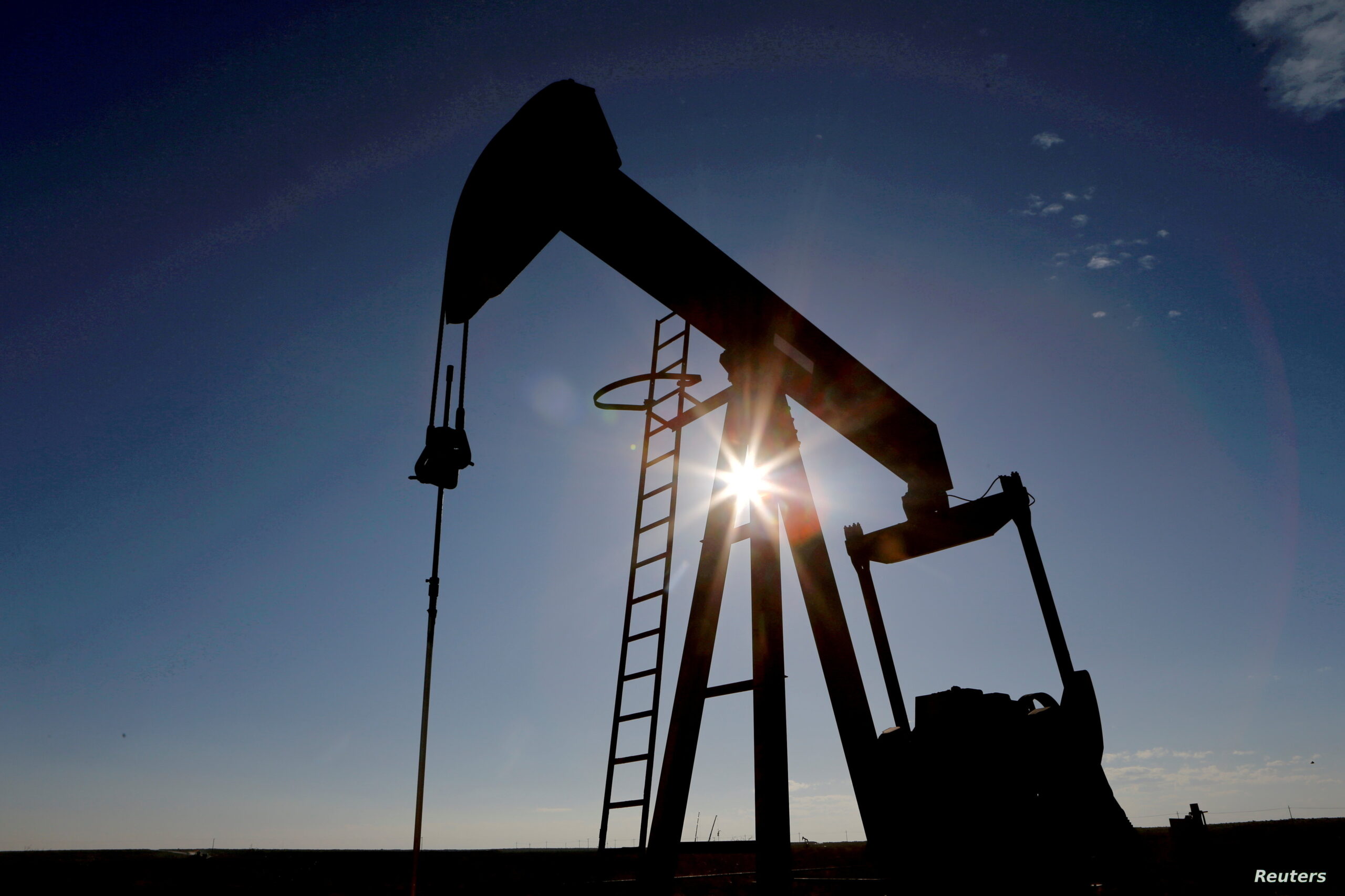 FILE PHOTO: The sun is seen behind a crude oil pump jack in the Permian Basin in Texas